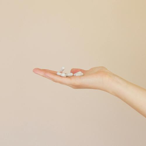 Pain killer comparison image, a hand holding pain killers with a beige background